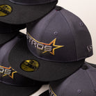 A stack of Black Delta City Connect Houston Astros New Era Hat 5950 Fitted baseball caps, each featuring a metallic gold and silver star logo.