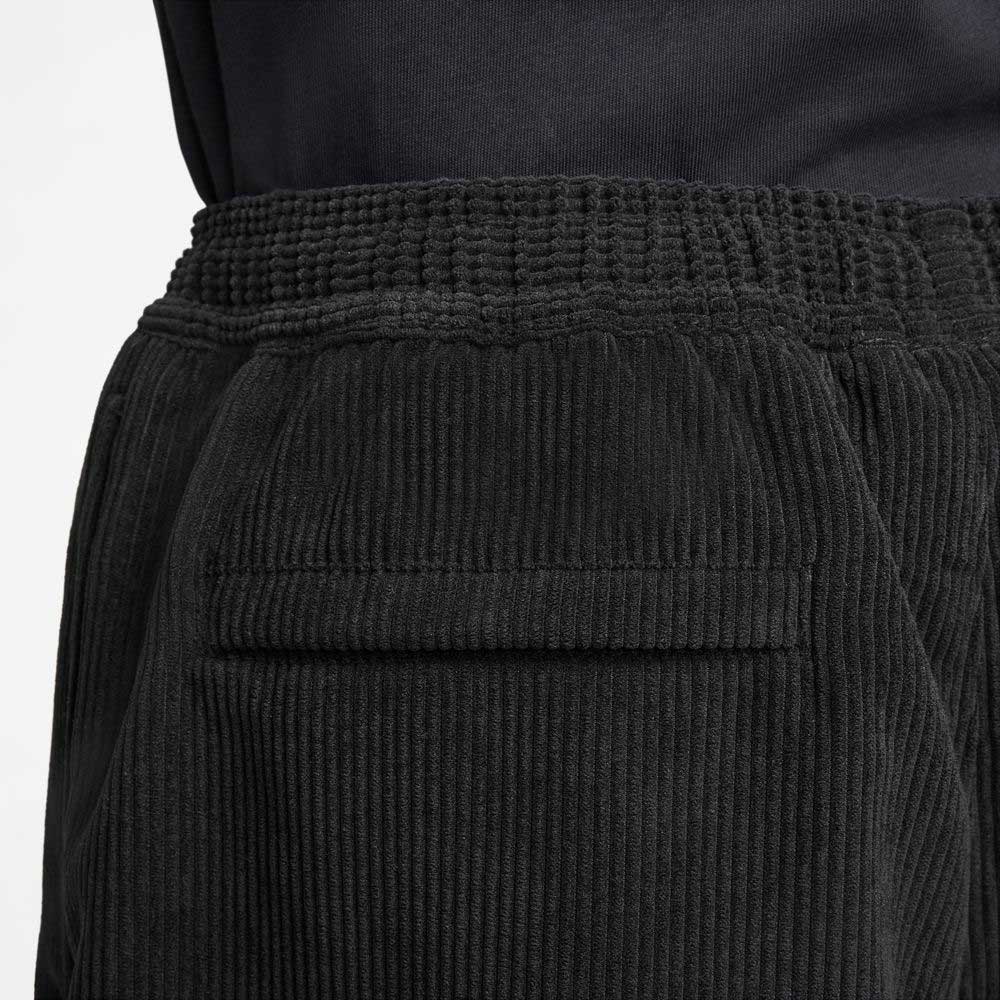 Close-up of the back of a person in II4426010 Black White Corduroy Skate Shorts Nike SB, featuring an elastic waistband and single welt pocket, paired with a dark shirt.