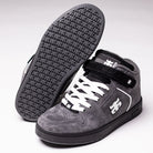 A pair of Grasshopper Gray Suede I Path Shoes for skateboarding, featuring black soles, white laces, and a side logo. One shoe stands upright while the other reveals its textured sole, evoking the classic Grasshopper silhouette.