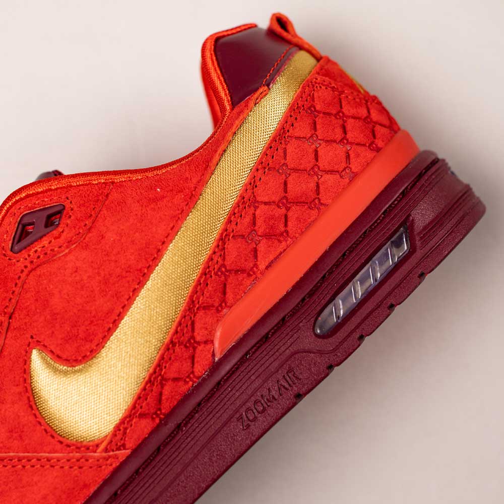 Close-up of the Nike SB Paul Rodriguez Zoom Air Low in Habanero Red/Club Gold/Team Red, featuring a suede and leather upper, gold swoosh, quilted stitching, and visible Zoom Air cushioning in the maroon sole.
