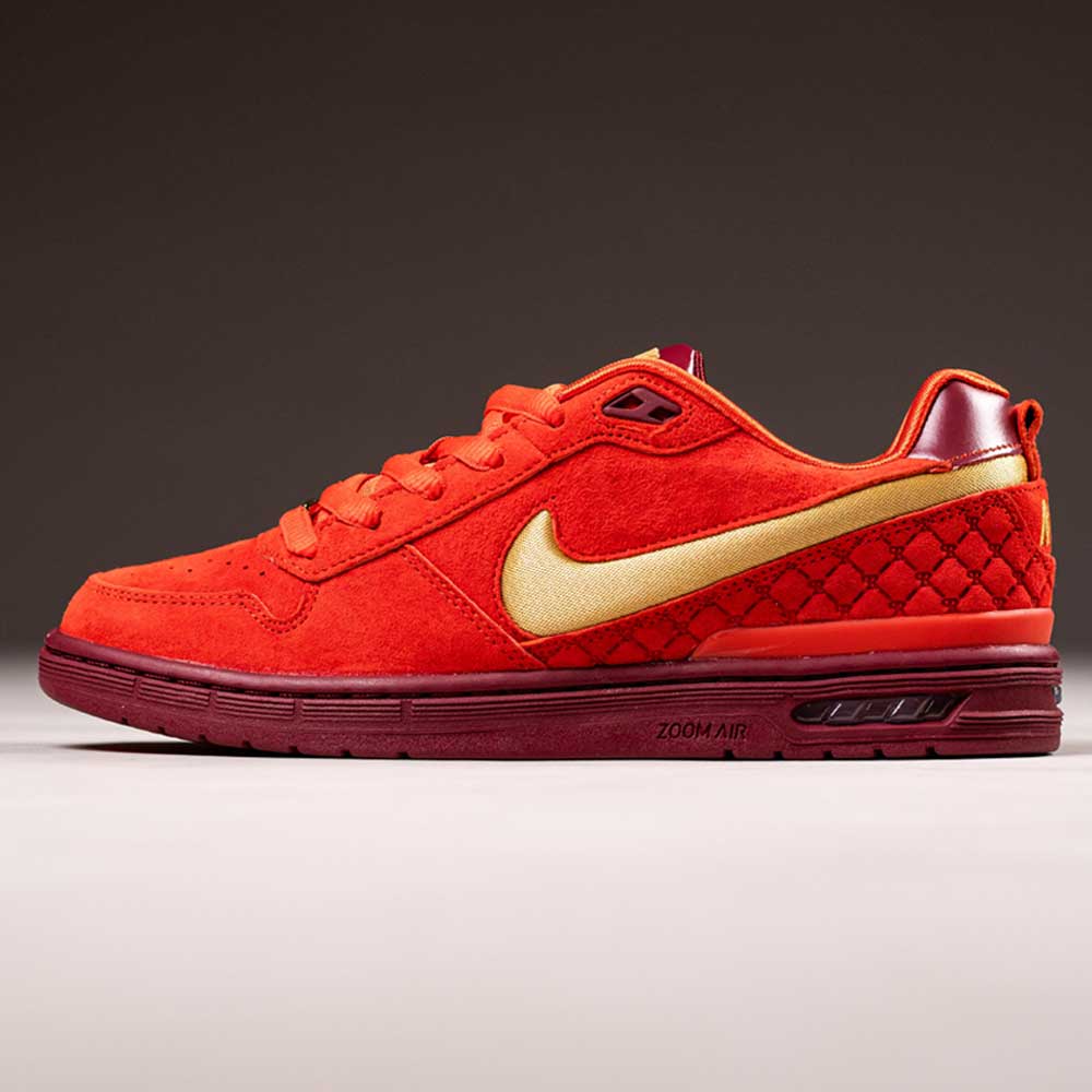 The IQ5648600 Nike SB Zoom Air Low skate shoe features Habanero Red suede, Club Gold swoosh, Team Red accents, a leather upper with quilted heel detail, and Zoom Air cushioning—all showcased against a neutral background.