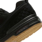 Close-up of the heel of the IQ6827001 Black Gum Light Brown Paul Rodriguez Zoom Air Low Suede Skateboarding Shoe, showing its textured black suede, visible Zoom Air cushioning, and a light brown gum outsole with a wavy tread.