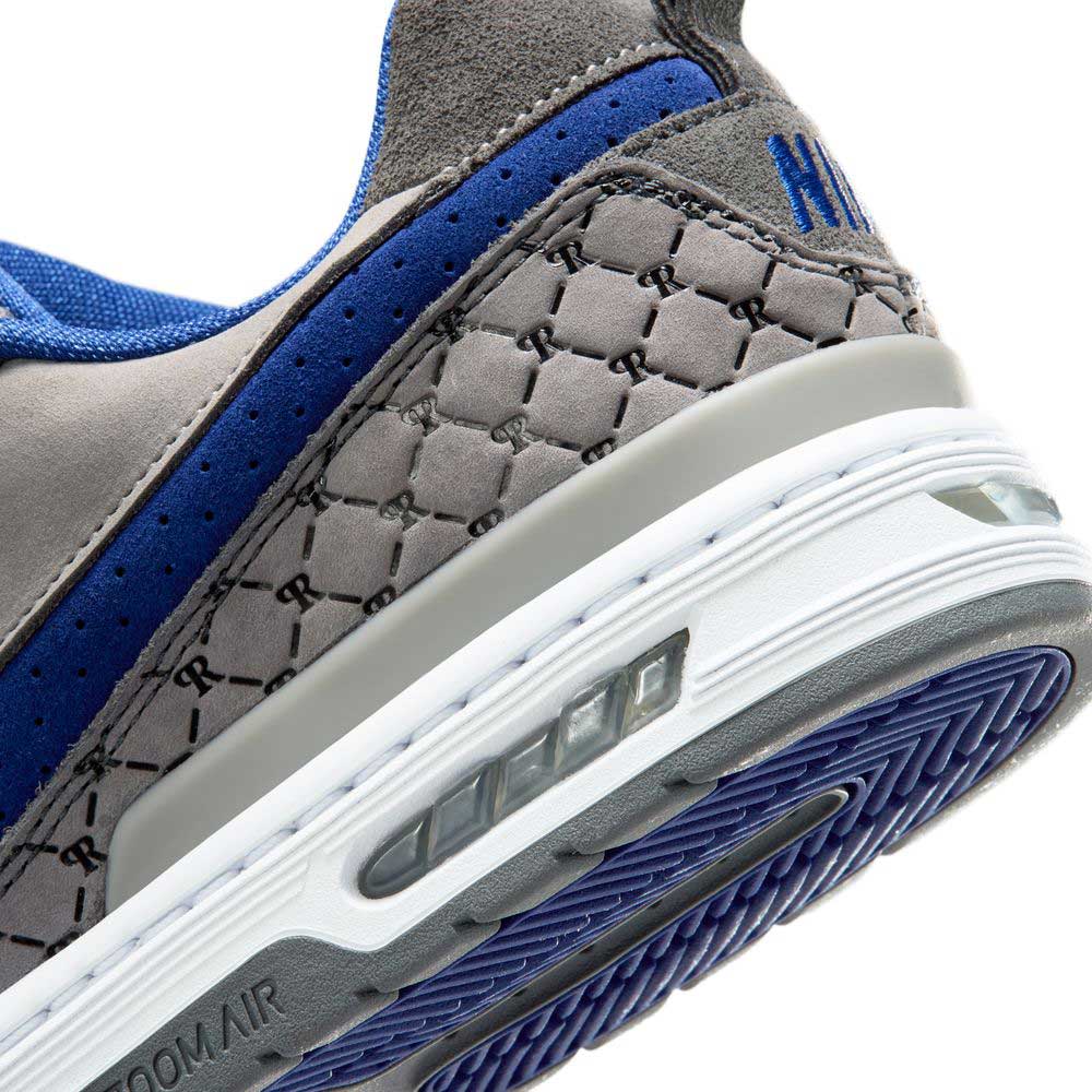 Close-up of the heel of the IU7835001 Flint Grey Deep Royal Blue Paul Rodriguez Zoom Air Low Suede Skateboarding Shoes, showing a suede upper, textured design, visible Zoom Air cushioning, detailed stitching, deep-groove outsole, and partially visible branding.