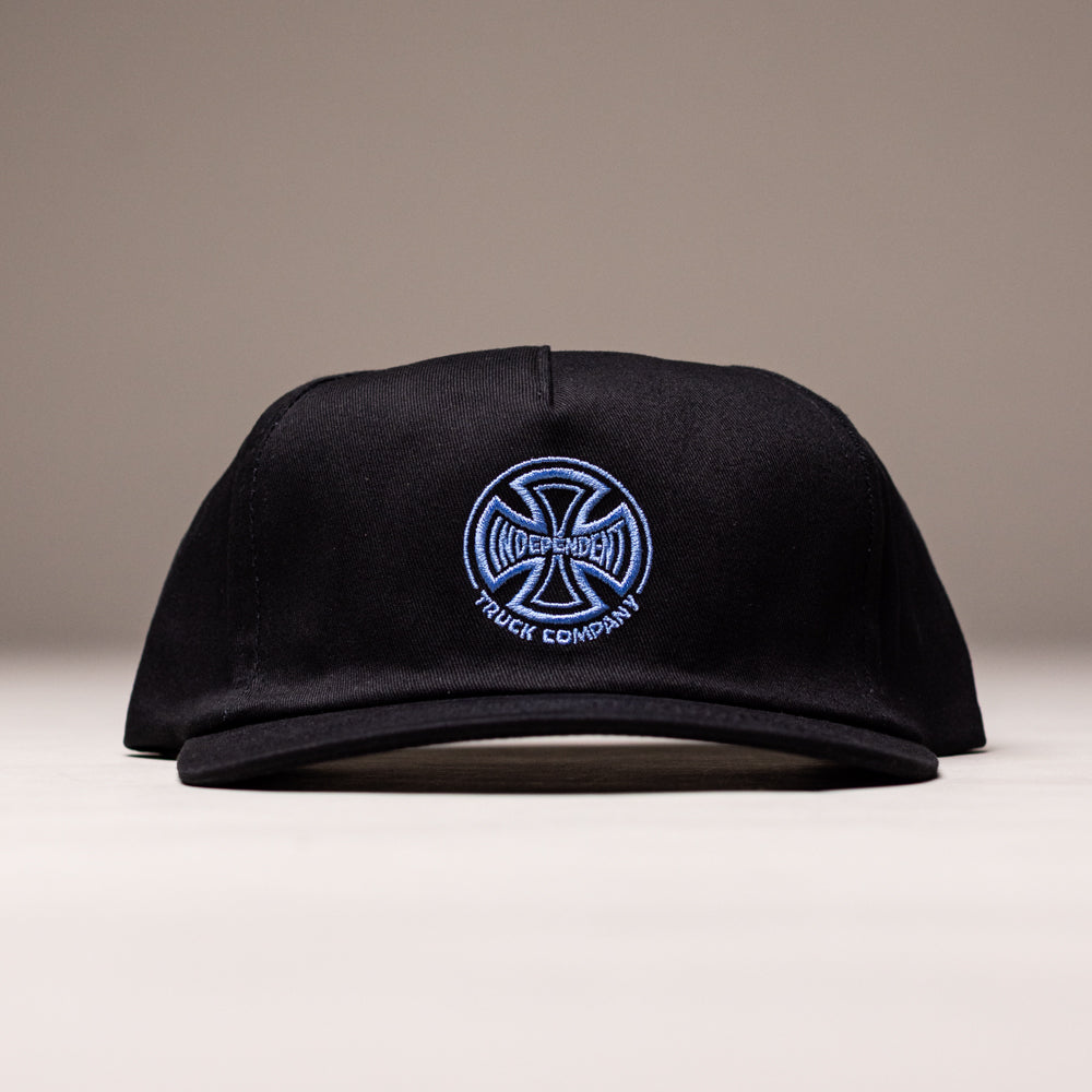 A black Independent Skateboards Truck Co Legacy unstructured snapback hat with a tan brim, featuring the embroidered logo on the front, shown against a neutral background. Unisex, one size fits most.