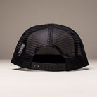 The OGBC Legacy White Dark Green Hat Shadow Snapback by Independent Skateboards is shown from the back, featuring an unstructured design and adjustable snap closure. The background is plain and neutral.
