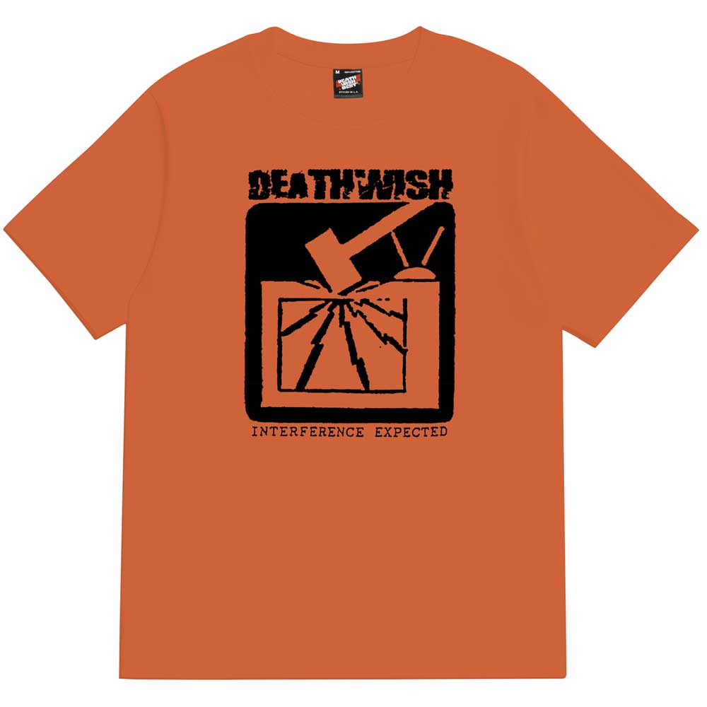 The Interference Tee Orange from Deathwish Skateboards features a striking black graphic of a hammer smashing a TV screen, with “DEATHWISH” above and “INTERFERENCE EXPECTED” below, delivering edgy style and unmistakable attitude.