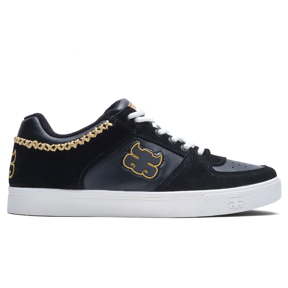 The Kenny Reed Low Vulc Black Leather Suede I Path Skateboarding Shoes feature a black and dark gray design with white laces, a white sole, gold stitching on the heel, and a bold gold side logo.