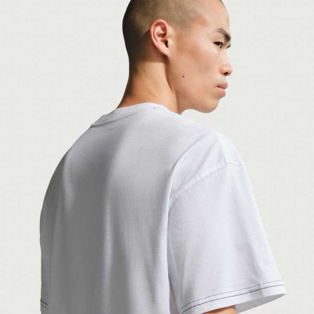 A person with a shaved head is shown from behind and slightly to the side, wearing the Ishod Tee White IH1437100 Nike SB T-Shirt, set against a light, neutral background.