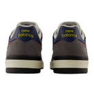 A pair of Jamie Foy Cup 306 CON New Balance Numeric Suede Skateboarding Shoes viewed from the back, featuring the brand’s yellow logo on gray, durable suede heels with navy, white, and red accents—designed for impact protection inspired by Jamie Foy skate shoes.