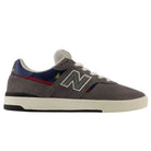 A side view of the Jamie Foy Cup 306 CON New Balance Numeric Suede Skateboarding Shoes in gray, featuring white laces, blue and red accents, a white midsole, black rubber cup outsole, and the iconic N logo—these durable suede skate shoes are designed for ultimate performance and style inspired by Jamie Foy.