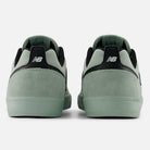 A pair of Mosaic Green Black Jamie Foy Mint 306 MOG New Balance Numeric suede skateboarding shoes seen from the back, with suede heels, black accents, and white logos—an ideal vulcanized shoe for skating.