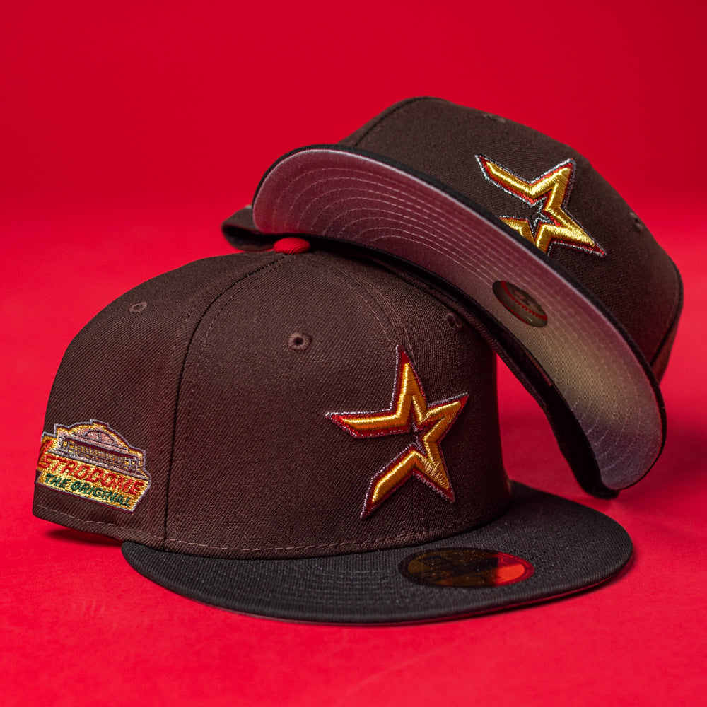 Two KB2 OG Wood Black The Original Houston Astros New Era 5950 Fitted hats, each featuring a gold star logo on the front and an embroidered side patch, are stacked against a solid red background.