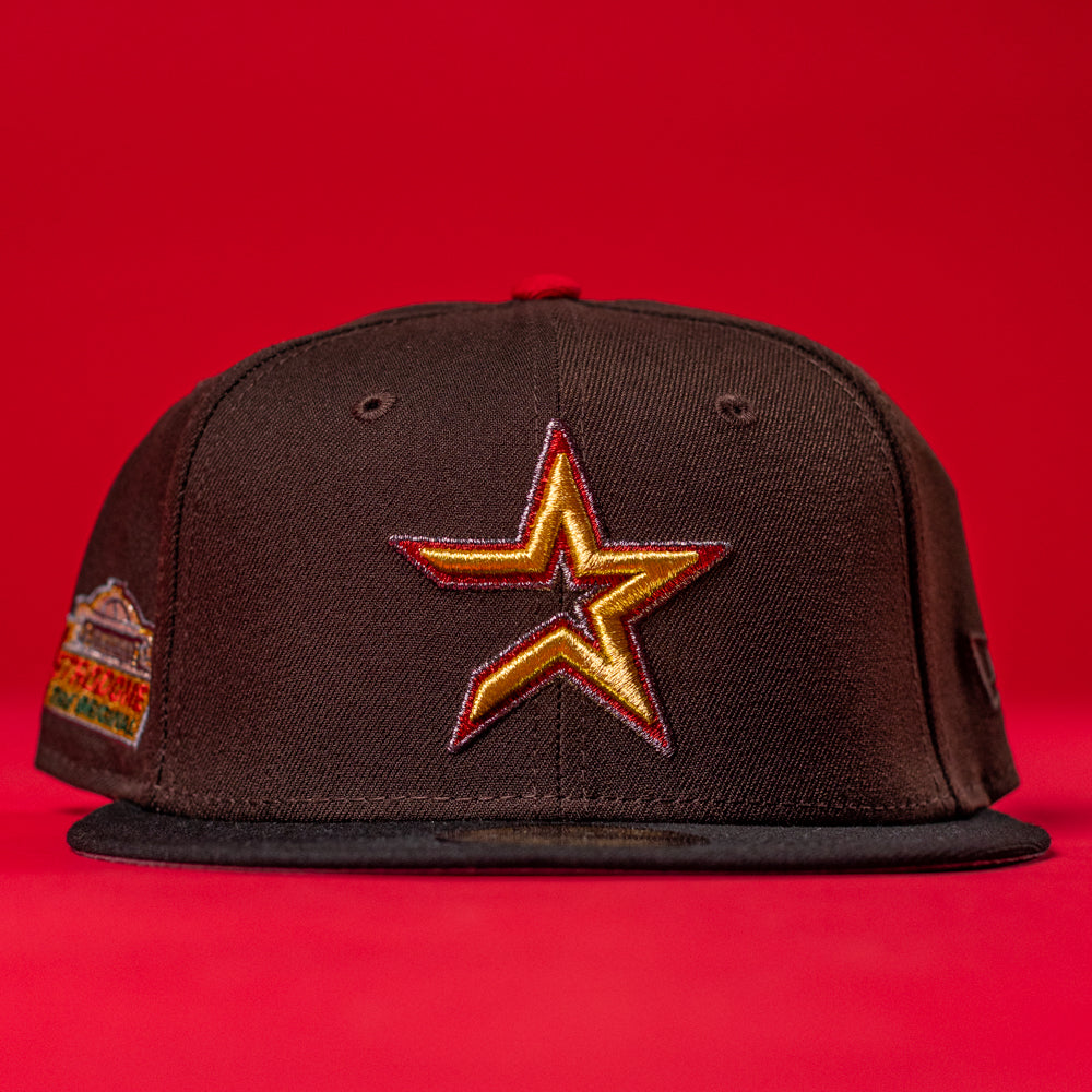The KB2 OG Wood Black The Original Houston Astros New Era Hat 5950 Fitted, with a yellow and red outlined star logo on the front, is displayed against a solid red background.