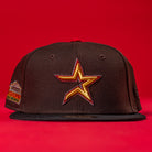 The KB2 OG Wood Black The Original Houston Astros New Era Hat 5950 Fitted, with a yellow and red outlined star logo on the front, is displayed against a solid red background.
