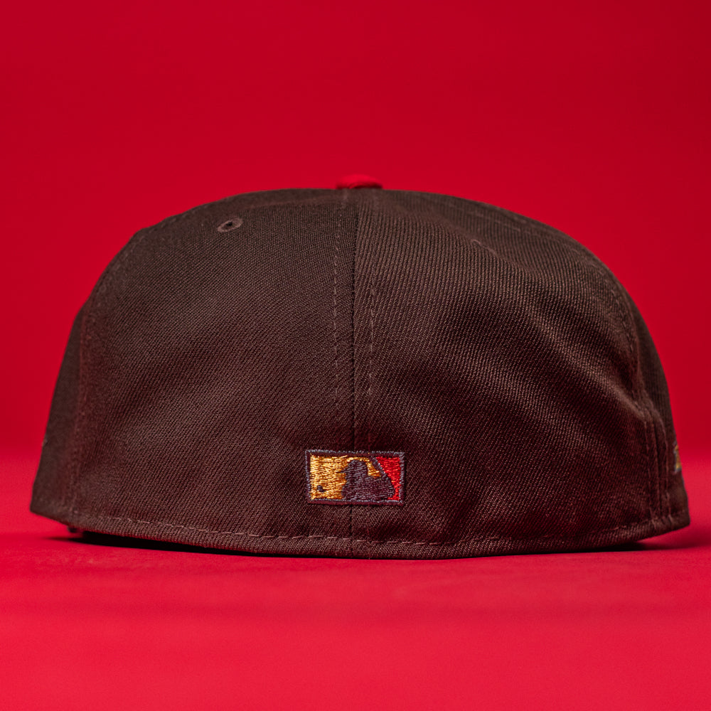 The KB2 OG Wood Black The Original Houston Astros New Era 5950 Fitted Hat is shown from the back against a red background, with a small embroidered logo in gold, red, and black near the bottom center of the cap.