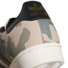 Close-up of the heel of the KJ5120 Camouflage Black Superstar ADV Adidas Skateboarding Suede Shoe, showing its camouflage pattern, white sole, black suede detail, and gold adidas trefoil logo with adidas text on the back.