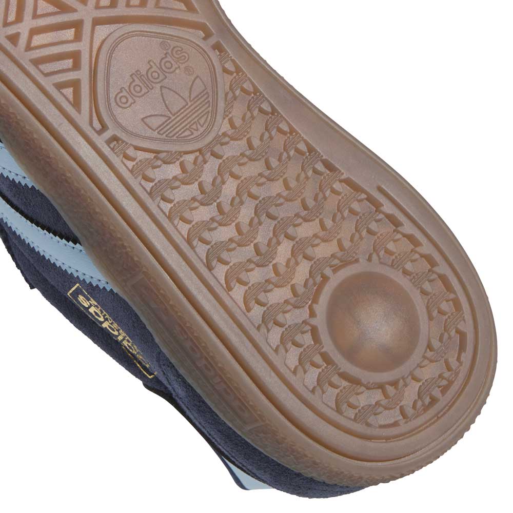 Close-up of the gum rubber tread on the Adidas KJ5478 Blue Gum Busenitz Vintage Skateboarding Suede Shoes, featuring the Adidas logo and part of the dark blue upper with a gold Samba label—ideal for skateboarding.