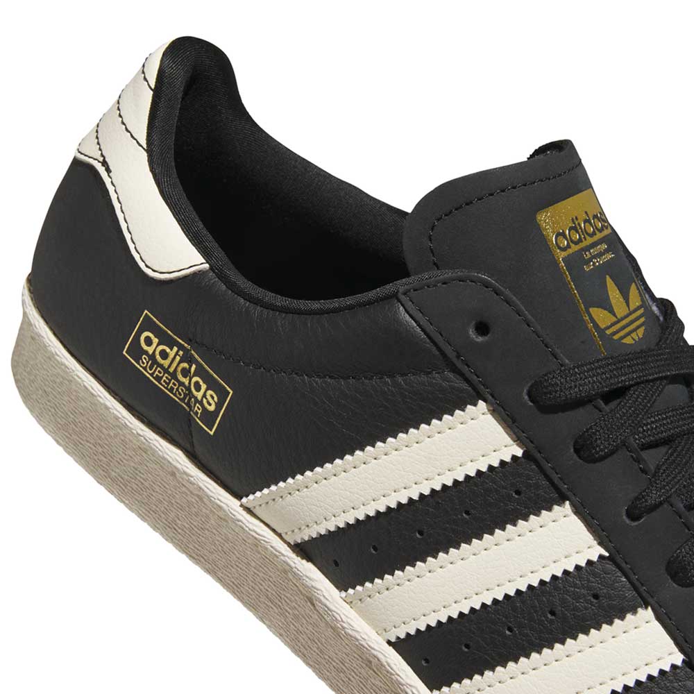 Close-up of KK5003 Black White Superstar 80 ADV Adidas Skateboarding Leather Shoes, featuring three white stripes, gold adidas branding on the side and tongue, and a classic textured white sole—style reimagined for skateboarding.