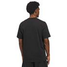 A man with short curly hair stands with his back to the camera, wearing a Kogan Dog Tee Black Blue KC6304 Adidas Skateboarding and black shorts against a white background.