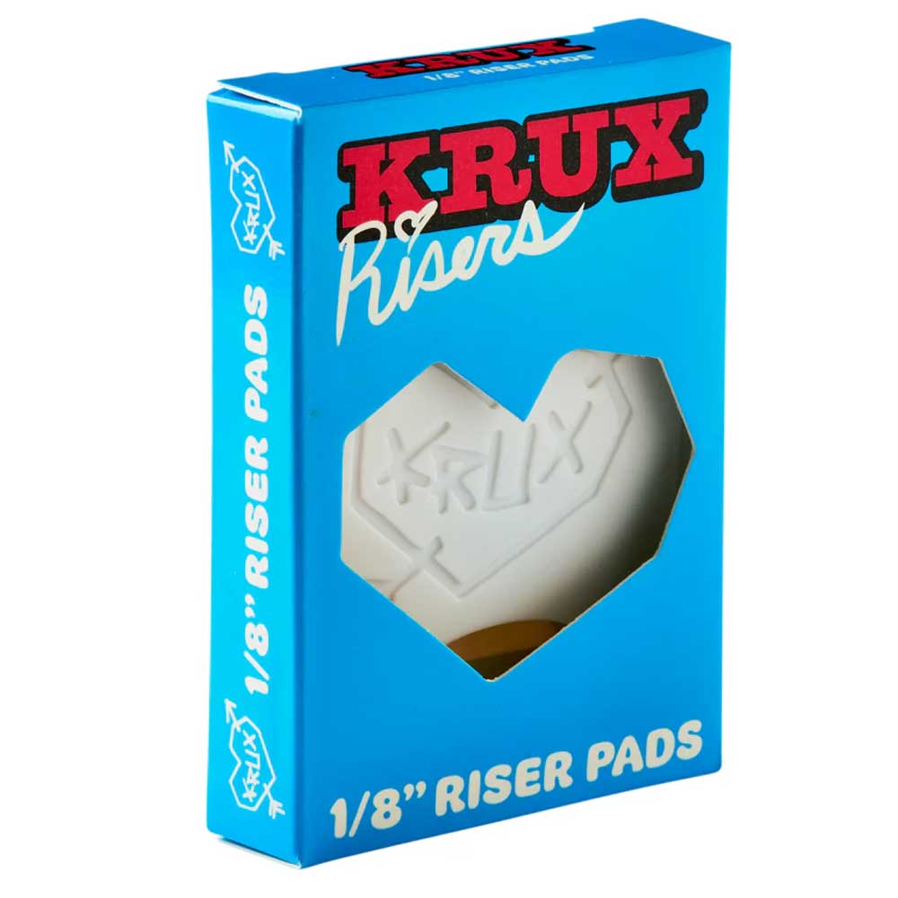 A blue box labeled "Krux 1/8 Inch White Riser Pad Set Pair" features a heart-shaped window showing the white riser pads inside, bold red and white text, and a stylized heart design—ideal for Krux Trucks or any skateboard riser setup.