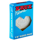A blue box labeled "Krux 1/8 Inch White Riser Pad Set Pair" features a heart-shaped window showing the white riser pads inside, bold red and white text, and a stylized heart design—ideal for Krux Trucks or any skateboard riser setup.