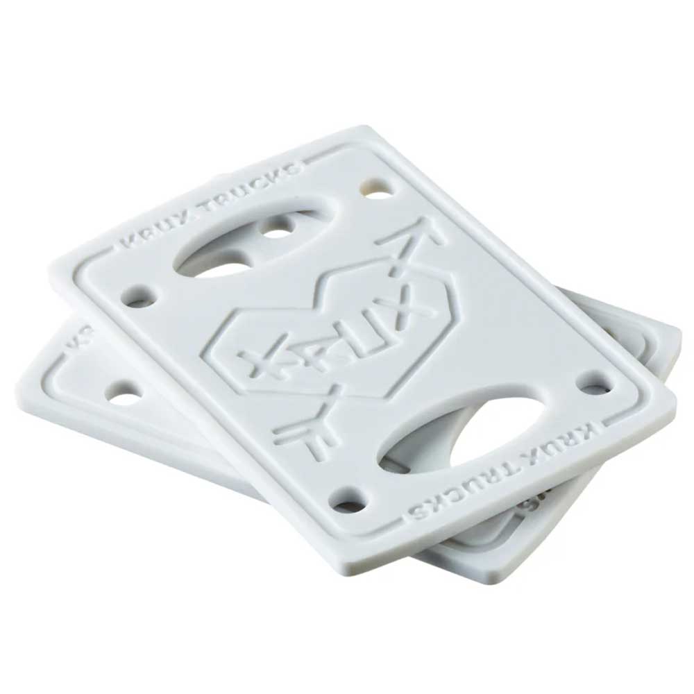 The Krux 1/8 Inch White Riser Pad Set Pair includes two white pads with embossed “KRUX” logos, four screw holes, and two truck bolt openings each, designed to fit between skateboard trucks and the deck for added clearance.