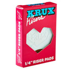A red box labeled "KRUX Risers" with a heart-shaped cutout displays the white Krux 1/4 Inch Riser Pad Set Pair inside, ideal for adding risers to your skateboard’s Krux Trucks setup.