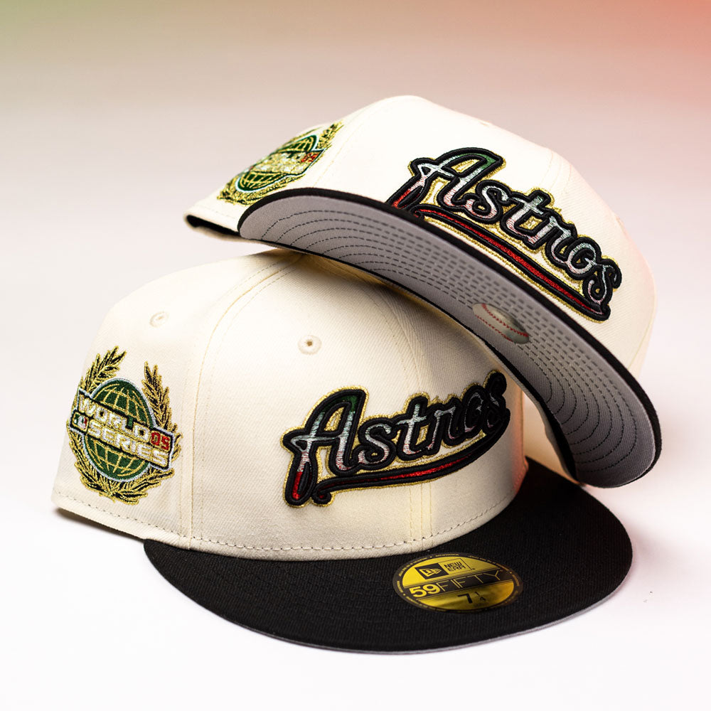 Two La Cumbia WS05 Chrome Black Mexico Houston Astros New Era 59FIFTY fitted hats, featuring embroidered logos and gold World Series patches, are stacked on a white surface against a subtle red and green gradient background.