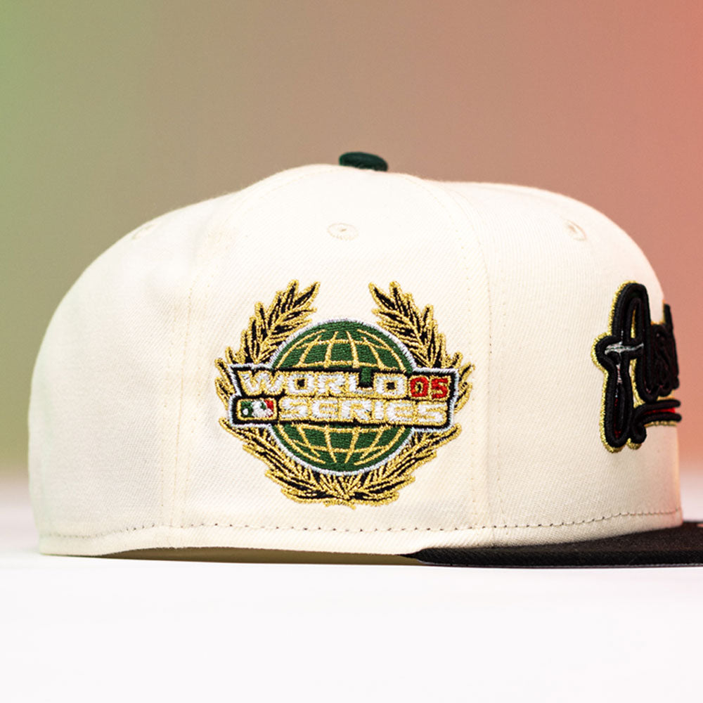 The La Cumbia WS05 Chrome Black Mexico Houston Astros New Era 59FIFTY Fitted Hat features a cream crown with a black brim and is adorned with a gold and green World Series logo patch depicting a globe and laurel wreath—an ideal accessory for Houston Astros fans.