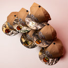 Five La Ofrenda Khaki RTC Copa Corpus Christi Hooks New Era 5950 Fitted hats, featuring camouflage brims and embroidered logos, are arranged diagonally on a pink surface, each with a sizing and branding sticker on the brim.