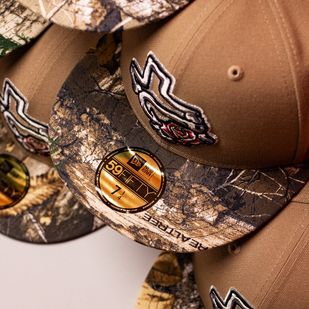 Close-up of stacked La Ofrenda Khaki RTC Copa Corpus Christi Hooks New Era 5950 fitted hats with gold brim stickers and embroidered rose design, ideal for fans and hat collectors.
