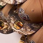 Close-up of stacked La Ofrenda Khaki RTC Copa Corpus Christi Hooks New Era 5950 fitted hats with gold brim stickers and embroidered rose design, ideal for fans and hat collectors.