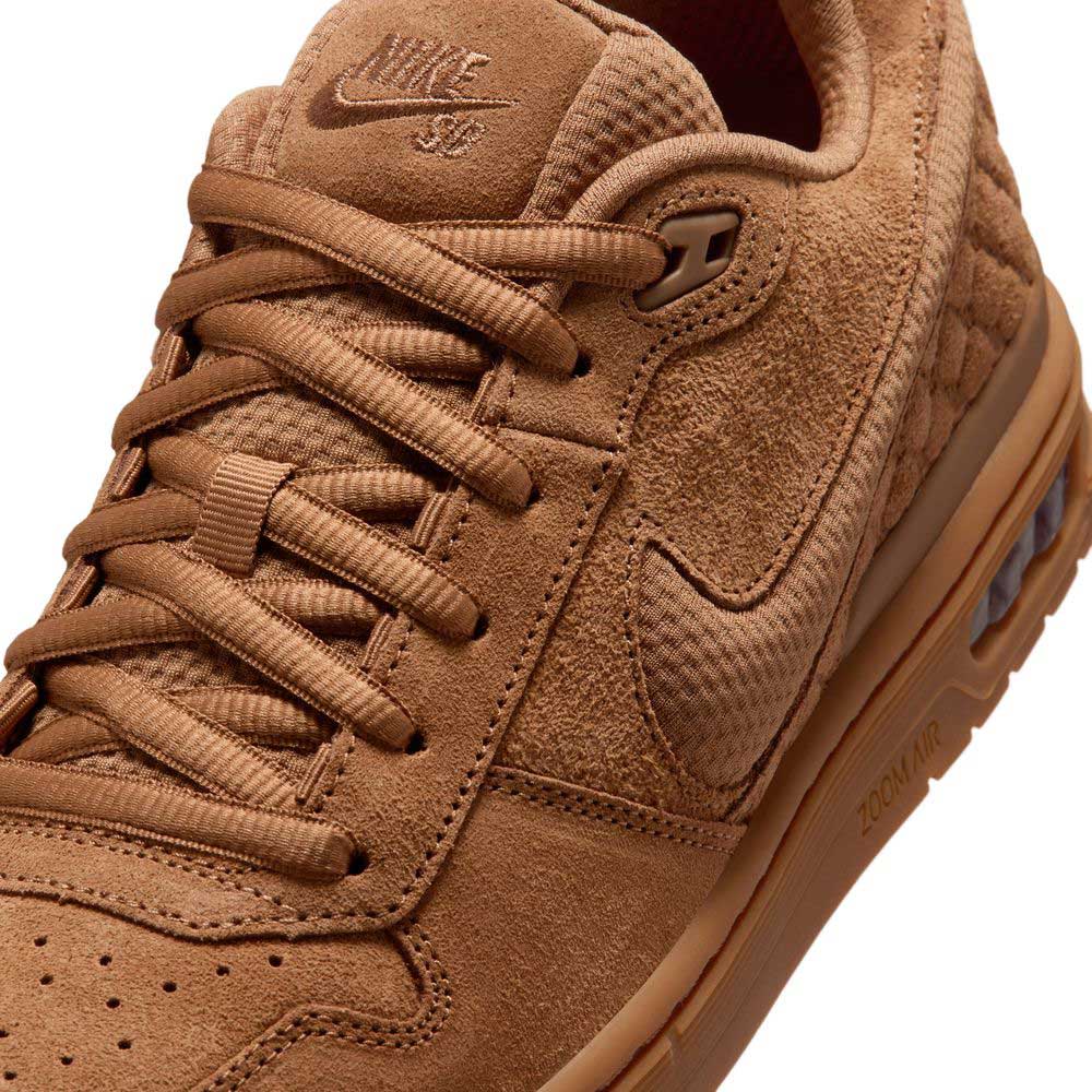 Close-up of the Light British Tan IQ6827200 Paul Rodriguez Zoom Air Low Suede Skateboarding Shoe by Nike SB, featuring rich brown suede and textured detailing, visible laces, an embroidered Nike logo on the tongue, prominent stitching, and a durable rubber outsole designed for enhanced traction.