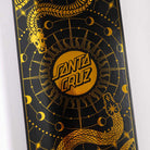 Close-up of the McCoy Snakes VX Deck 8.25in x 31.83in by Santa Cruz Skateboards, showcasing a gold geometric snake and celestial design with moons and "Santa Cruz" centered on a black background.