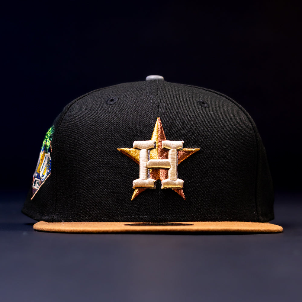 The Midsummer Night 26 Spring Bronze Houston Astros New Era 5950 Fitted Hat features a black design with a tan brim, gold star and white H embroidery, decorative stitching, inspired by the Houston Astros.