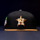 The Midsummer Night 26 Spring Bronze Houston Astros New Era 5950 Fitted Hat features a black design with a tan brim, gold star and white H embroidery, decorative stitching, inspired by the Houston Astros.