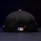 The Midsummer Night 26 Spring Bronze Houston Astros New Era 5950 Fitted cap is shown from the back, with the MLB logo embroidered at the center and three small star-shaped stitches to the right, set against a dark background.
