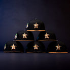 Six Midsummer Night 26 Spring Bronze Houston Astros New Era 5950 Fitted hats with gold logos, yellow brims, and side patches are arranged in a pyramid formation against a dark background.