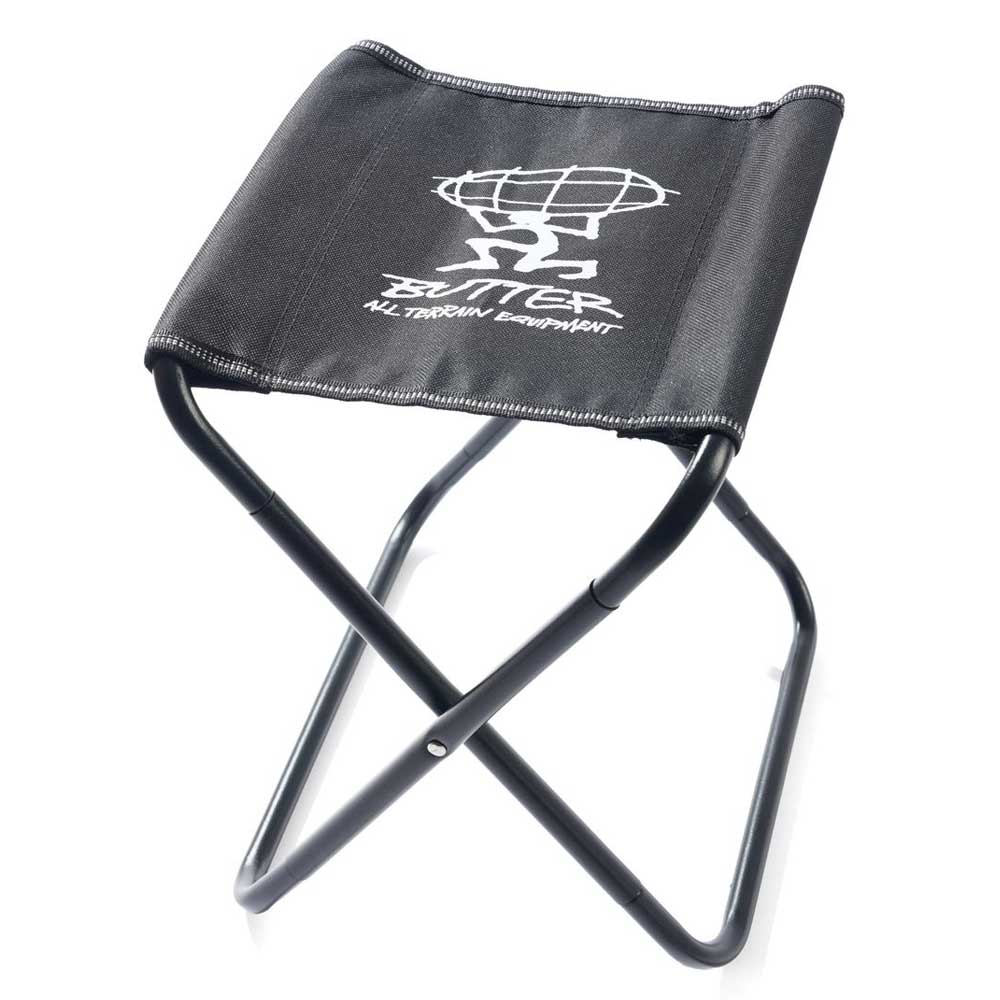 The Mini Packable Camping Chair Black by Butter Goods features a sturdy aluminum alloy frame, black fabric seat with a white globe-and-person graphic, and "BUTTER ALL TERRAIN ENTERTAINMENT." Lightweight and foldable—ideal for camping.