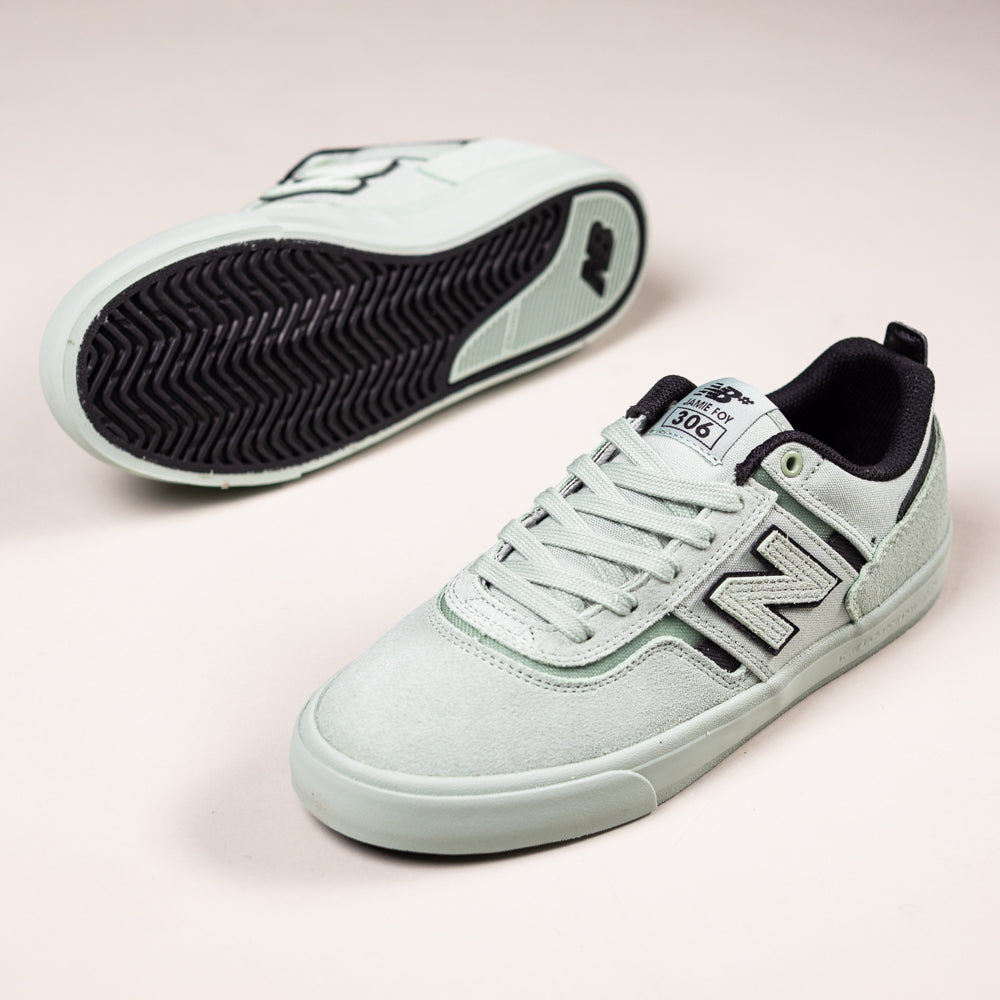 A pair of Jamie Foy Mint 306 MOG New Balance Numeric suede skateboarding shoes in light gray with black detailing and soles, shown on a plain background. One shoe is upright, the other on its side displaying the sole and "N" logo.