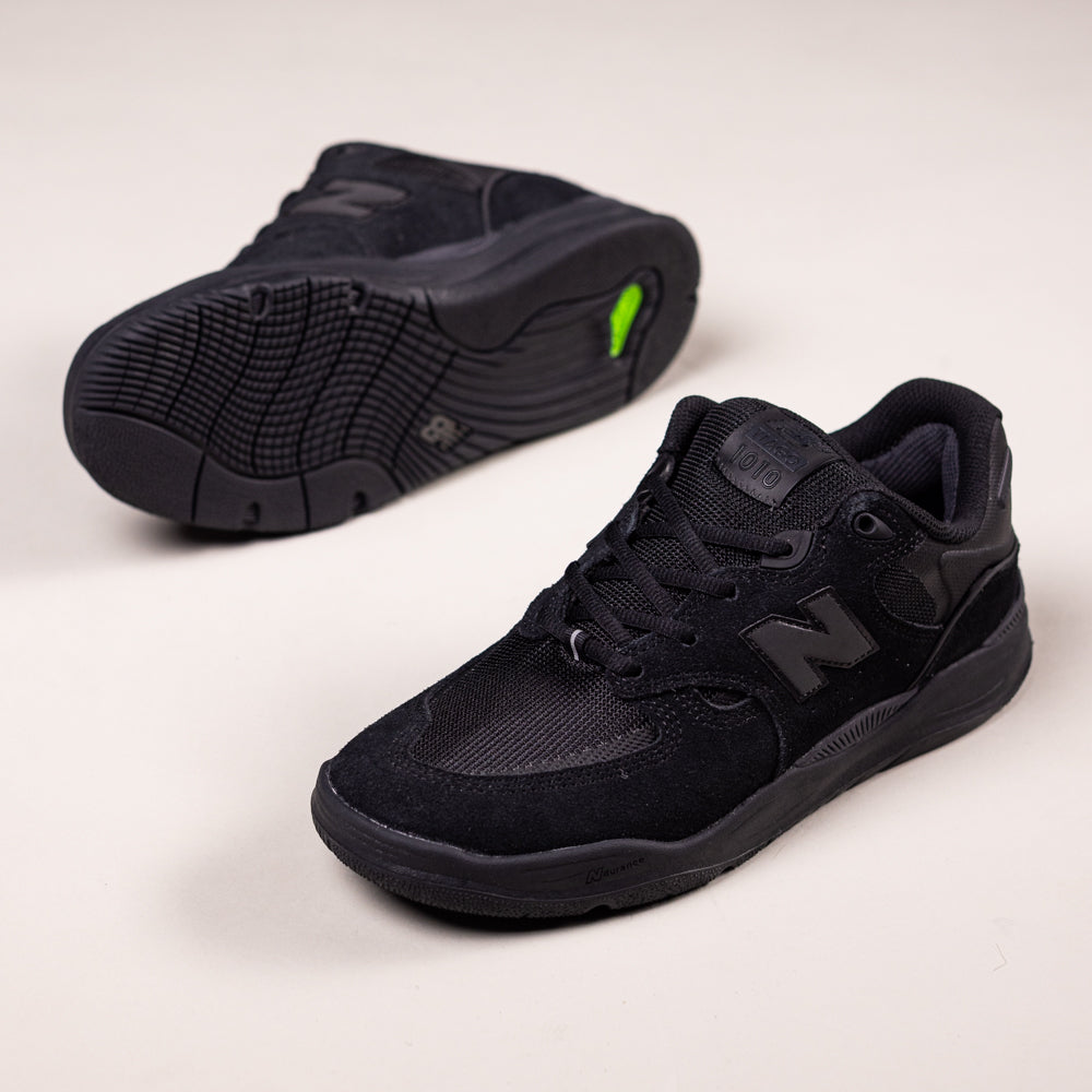 A pair of 1010 CR Black New Balance Numeric Suede Skateboarding Shoes featuring a durable ABZORB midsole displayed on a light background; one shoe is upright showing the top and side, the other reveals the sole.