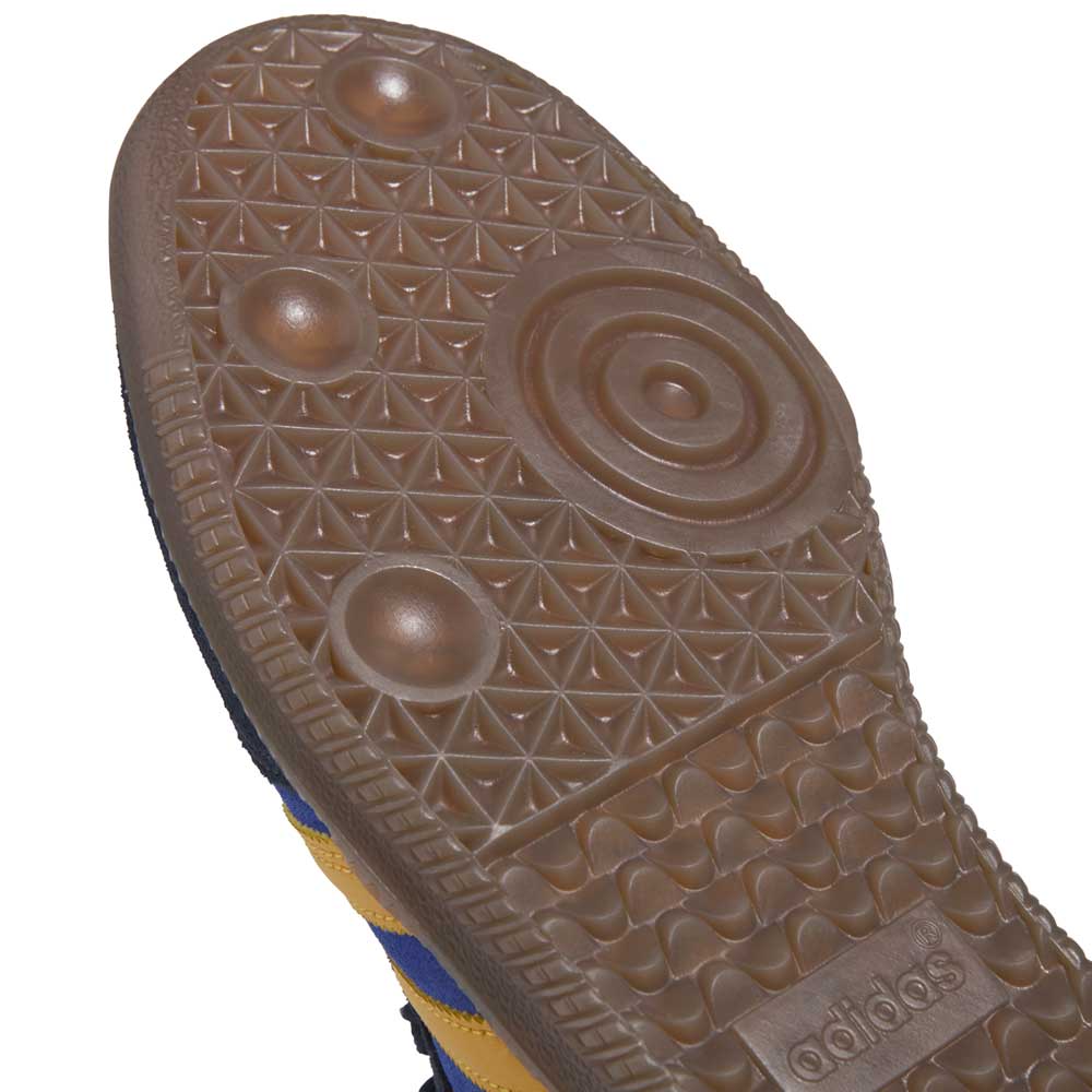 Close-up of the gum rubber sole on the Navy Yellow Gum Samba ADV HQ9283 Adidas Skateboarding Leather Suede Shoe, featuring a textured circular pattern and embossed logo. The blue and yellow upper highlights adidas innovation.