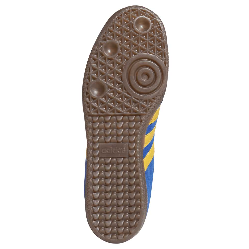 The image shows the sole of the Navy Yellow Gum Samba ADV HQ9283 Adidas Skateboarding Leather Suede Shoes, featuring a brown rubber tread with circular and diamond patterns, blue sides with yellow stripes, and the Adidas logo embossed on the sole.