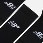 Three New Balance Numeric 3 Pack Socks Black (AC0048UBK) with white abstract logo near the top, featuring geometric shapes and lines, are arranged diagonally on a plain background. Each pair includes a cushioned footbed for comfort.