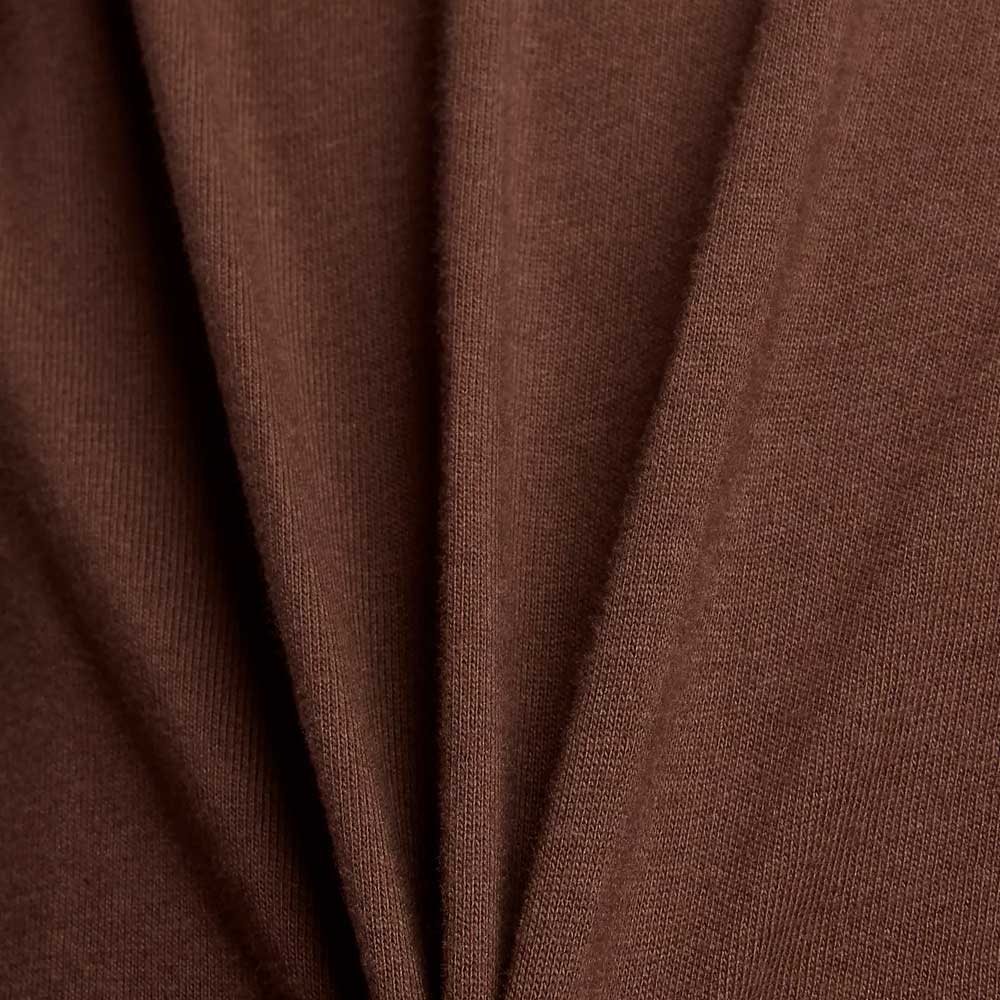 Close-up of soft brown folds form diagonal lines and shadows, emphasizing the relaxed fit and texture of the New Balance Numeric Small Logo Tee Pumperknickel MT53706ABJ—ideal for a casual crewneck style.