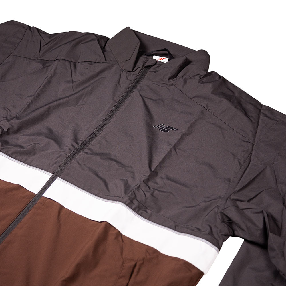 The New Balance Numeric Jacket MJ61W4XCABR features a color-blocked design in dark gray, white, and brown ripstop fabric, with a small embroidered chest logo and front zipper.