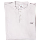 A folded, white New Balance Numeric Waffle Knit Tee MT51958GYM features long sleeves, a waffle-knit texture, three buttons, an embroidered logo on the left chest, and a visible medium size tag.