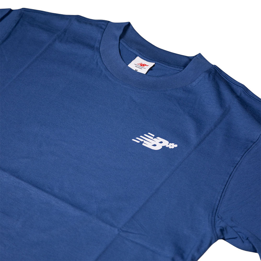 The New Balance Numeric Small Logo Magic Blue Tee MT53706AA4 is a cotton crewneck with a relaxed fit, featuring a small white New Balance logo with motion lines on the left chest and a visible inner neck tag.