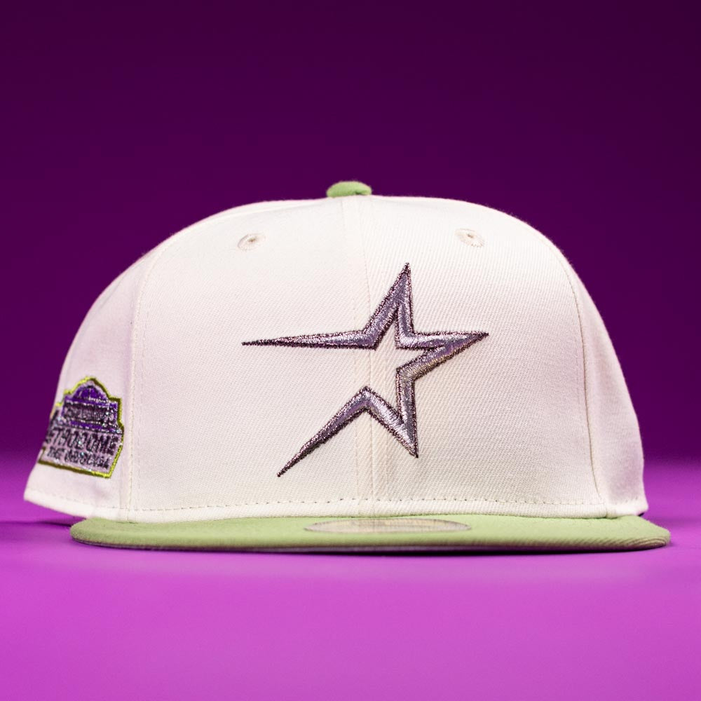 The Matcha Guy Houston Astros New Era Hat 5950 Fitted by New Era features a cream color, silver star front logo, light green brim, and a left-side patch, shown on a purple surface with a purple background.