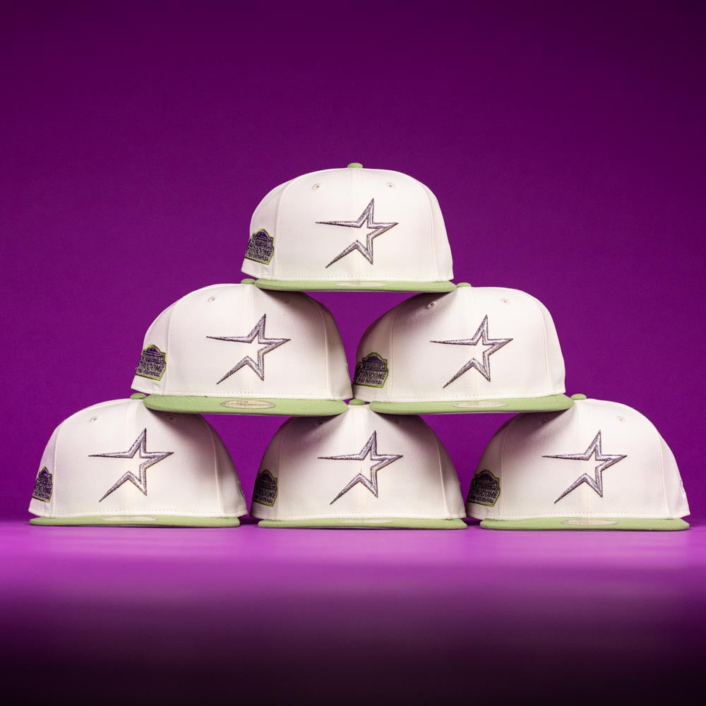 Six Matcha Guy Houston Astros New Era Hat 5950 Fitted caps, in white and green with the star logo and side patches, are stacked in a pyramid against a purple background.